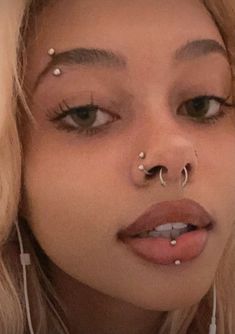 a close up of a person with piercings on her nose and nose ring in front of their face