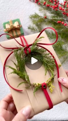 someone is holding a present wrapped in brown paper and tied with red ribbon around it