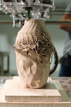 a sculpture of a human head on top of a block of wood with wires coming out of it