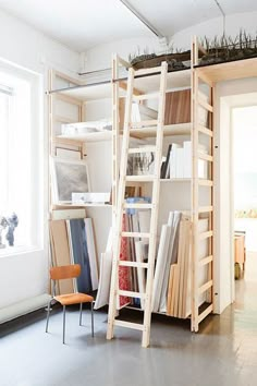 a ladder leaning up against a bookshelf in a room with white walls and flooring