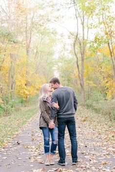 an engaged couple standing in the middle of a leaf covered path during their fall engagement session