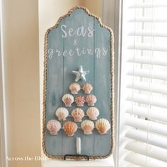 seas and greetings sign with sea shells on it in front of a white window