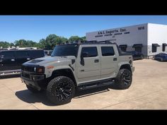 a white hummer truck parked in front of a large building with other trucks behind it