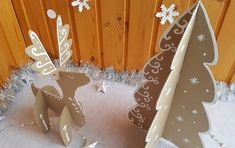 two paper christmas trees sitting on top of a white cloth covered ground with snowflakes