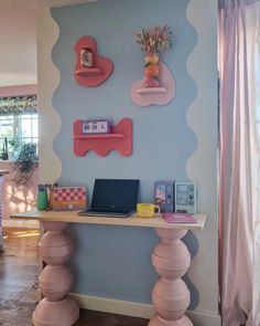 a laptop computer sitting on top of a wooden desk in front of a blue wall