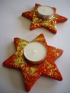 two red and gold star shaped cookies next to a white candle