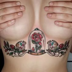 a woman's chest with tattoos on it and roses in a glass case under her breast