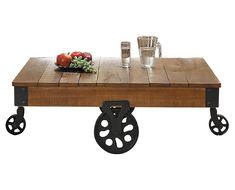 a coffee table with wheels on it and a bowl of fruit sitting on the top