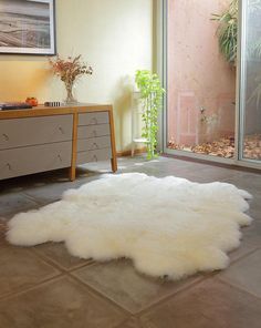 a large white sheepskin rug on the floor in front of a sliding glass door