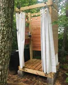 an outdoor shower in the woods with curtains