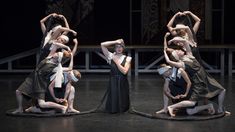 four dancers are performing on the stage with their arms in the air