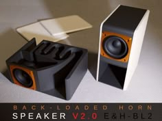 two speakers sitting next to each other on top of a white surface with text reading back - loaded horn speaker v2, e & bl2