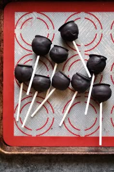 chocolate lollipops on a red tray with white sticks