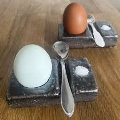 an egg and spoon sitting on top of a wooden table next to two salt shakers