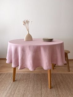 a table with a vase and plate on it in front of a white wall,