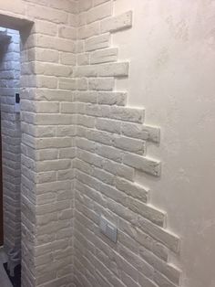 a bathroom with white brick walls and a toilet next to a door in the corner