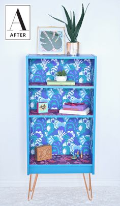 a blue book shelf with books and plants on top