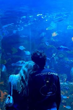 a man and woman looking at fish in an aquarium