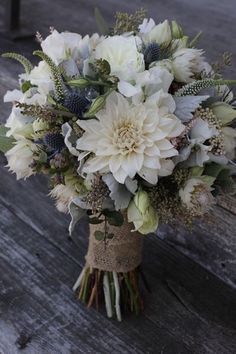 a bouquet of white flowers sitting on top of a wooden table next to a bench