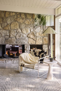 a living room with a stone fireplace and chair