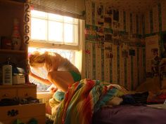 a woman is looking out the window in her bedroom