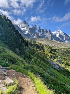 a trail in the mountains with grass and rocks on either side that leads to a mountain range