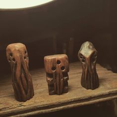 three carved wooden objects sitting on top of a wooden shelf next to eachother