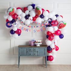 an arch made out of balloons with strawberrys and other decorations on top of it