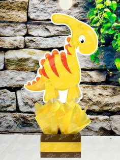 a paper cut out of a yellow dinosaur on top of a box filled with candy