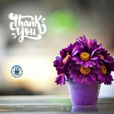 a purple vase filled with flowers sitting on top of a table next to a thank you sign