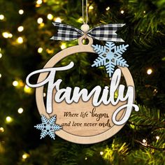 a wooden ornament with the words family hanging on a christmas tree in front of lights