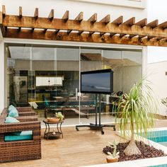 an outdoor living area with wicker furniture and a flat screen tv on the wall