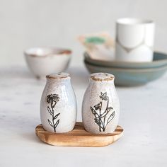 two white vases sitting on top of a wooden tray