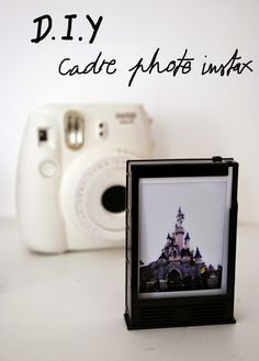 a white camera sitting next to a photo frame with a castle on it's side