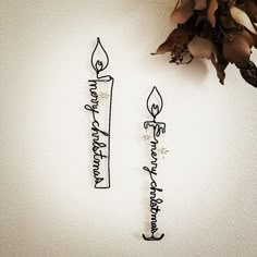 two metal candles sitting next to each other on top of a white wall with flowers