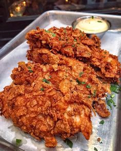 two fried chicken pieces on a metal tray