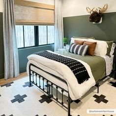 a bed room with a neatly made bed and a deer head mounted on the wall