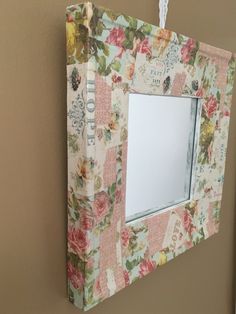 a mirror hanging on the side of a wall with flowers and words painted on it