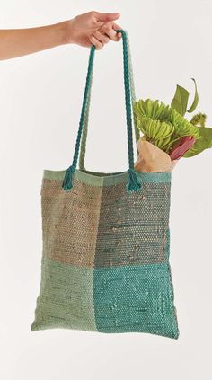 a person holding a bag with flowers in it and a handbag hanging from the ceiling