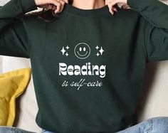 a woman is sitting on the couch with her hands behind her head and reading is self - care