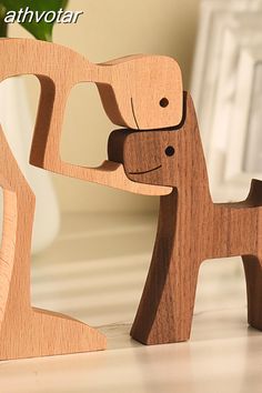 two wooden toy animals are standing next to each other on a table in front of a mirror