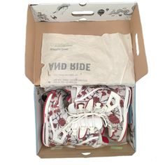 an open cardboard box with white shoes in the bottom and red print on the inside