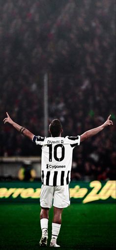 a man standing on top of a soccer field holding his arms up in the air