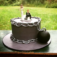 a wedding cake with a bride and groom figurines on top, sitting in the grass