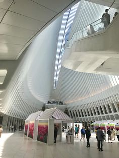 people are walking around in the lobby of a modern building with white walls and ceilings