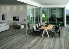 an open living room and dining area with wood flooring, glass walls and sliding doors