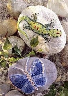 two rocks with designs on them sitting next to some leaves and stones in the sand