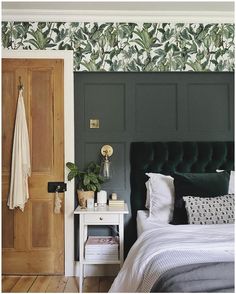 a bedroom with green and white wallpaper, a black headboard and a bed