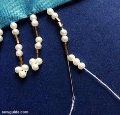 the beads are being sewn together to make a beaded necklace with metal pins