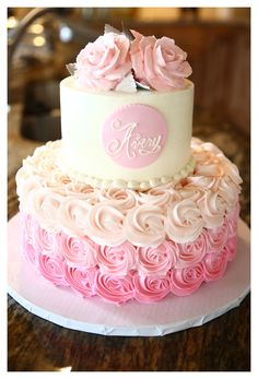 a three tiered cake with pink and white frosting roses on it's side